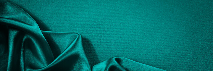 Wall Mural - Blue green silk satin background. Soft wavy folds on smooth, shiny fabric. Dark teal luxury background with copy space for design. Web banner.