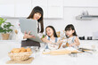 © metha275 - Mother show step of baking in laptop to child for make bread in the kitchen at home.