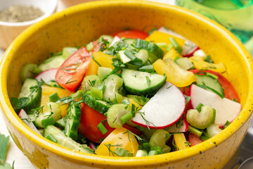 Wall Mural - Fresh vegetables salad with radish, cucumber, bell pepper, tomato, celery and greens in ceramic bowl on white wooden rustic background