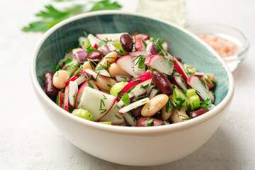 Wall Mural - Vegetable salad with radish, celery, red onion, beans and greens in bowl on concrete background