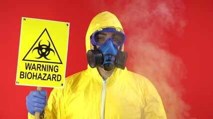 Wall Mural - Man in Protective Chemical Suit, Mask and Banner in Hands. Biological Protection. Negatively Shakes Head. Smoke Around Man. Isolate, Studio.