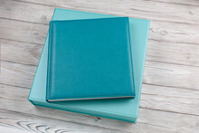 Blue Leather Photo Album On Cardboard Box.
Family Photo Book With Leather Cover In Gift Box With Ribbon.
Stylish Box With Photoalbum On Wooden Background. Square Photobook With Space For Text