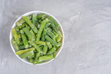 Top View Of Fresh Frozen Green Beans Vegetables Covered With Frost Served In White Bowl Preserving All Vitamins And Health Benefits Standing On Gray Concrete Background. Image With Copy Space