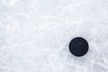 Wall Mural - Black old rubber puck on ice background. Closeup. Empty place for text. Top down view.