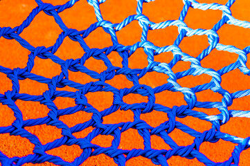 Closeup shot of a blue net in the playground with an orange background