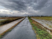 Empty Road Amidst Field Against Sky During Rainy Season