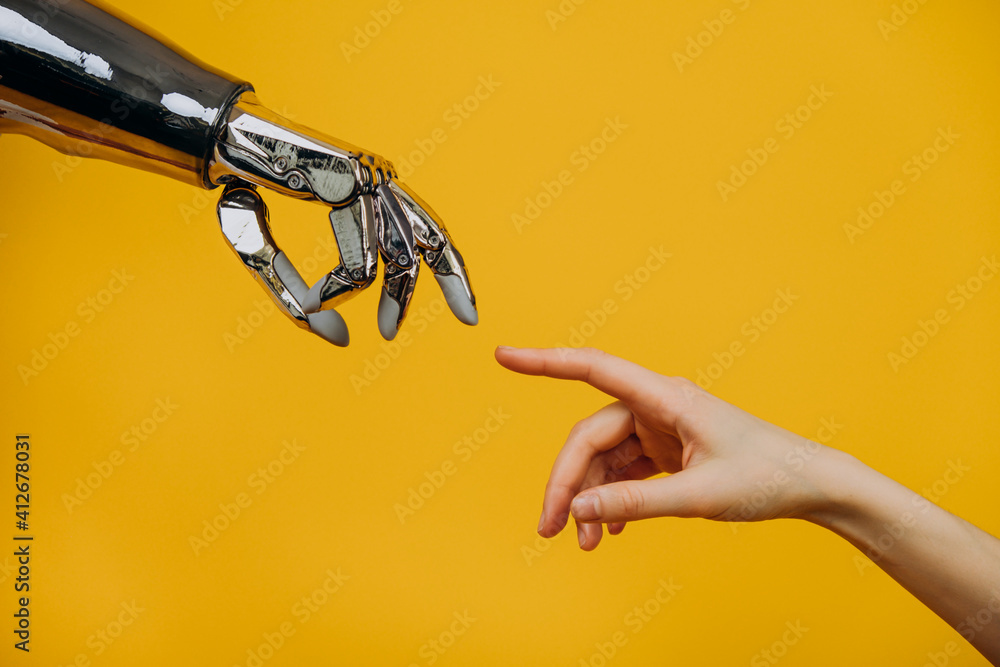 Robotic bionic hand and a woman's hand pulling fingers together on a yellow background close-up, the concept of human interaction and modern technology - obrazy, fototapety, plakaty 