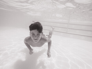 Boy swimming under blue water in pool