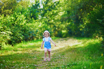 Wall Mural - Adorable toddler girl having fun outdoors on a sunny summer day