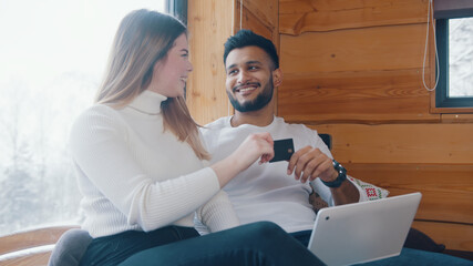 Young woman stealing credit card from her boyfriend. Playful fight and online shopping. High quality photo