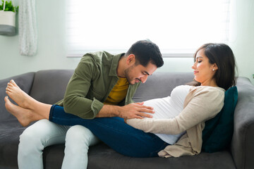 Wall Mural - Adorable latin man touching his pregnant wife's belly