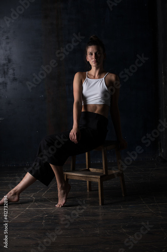 Portrait Of Beautiful Woman Sitting On Chair Against Wall