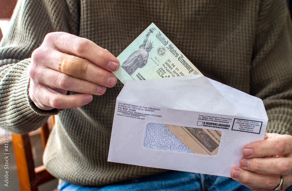  A man hand is Holding a  economic aid check during covid lock down