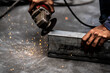 © Fikry Anshor/Wirestock - Closeup shot of a man holding an electric steel cutter on metal