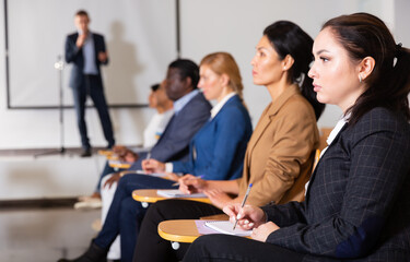 Sticker - Young focused woman sitting and listening to speaker at business conference