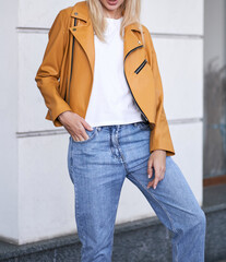 Wall Mural - Woman wears yellow jacket during fall season. Beautiful blonde girl standing in the casual style street wear. Successful woman template