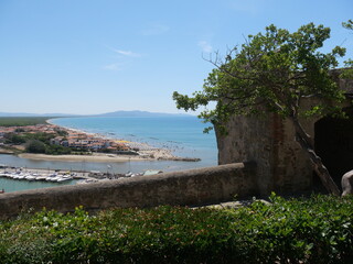 Wall Mural - Internal part of the fortifications of Castiglione della Pescaia. In the foreground the surrounding wall and ramparts and in the background the coast lapped by the Tyrrhenian Sea