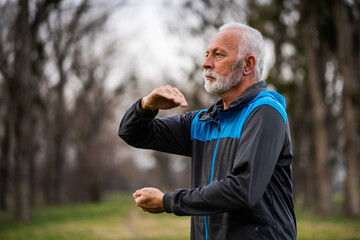 Senior man is practicing Tai Chi exercise in park.