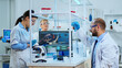 © DC Studio - Team of medical research scientists conducting vaccine development with help of microscope, test tubes, micropipette and writing down analysis results on clipboard in modern equipped laboratory