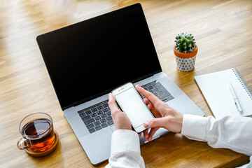 The man works with modern technologies, a laptop and a mobile phone. Top view of a programmer or businessman working in a cozy bright office