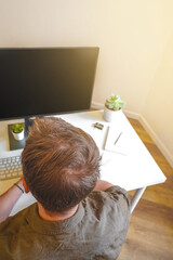 Wall Mural - a male programmer works in front of a laptop screen in a bright office or remotely from home. workpl