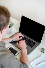 Wall Mural - a male programmer works in front of a laptop screen in a bright office or remotely from home. workpl