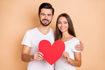 Poster - Portrait of handsome guy pretty lady hug hands hold red paper heart card isolated on beige color background