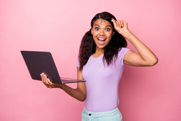 Sticker - Portrait of attractive amazed cheerful girl holding in hand laptop having fun isolated over pink pastel color background