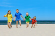 © Trutta - Two girls and two boys in colorful t-shirts walking on a sandy beach