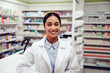 Happy successful woman working in a pharmacy wearing labcoat smiling at camera