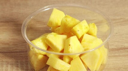 Canvas Print - female hands put in bowl fresh ripe pineapple fruit pieces and  at domestic kitchen for making healthy breakfast smoothie. home cooking close up