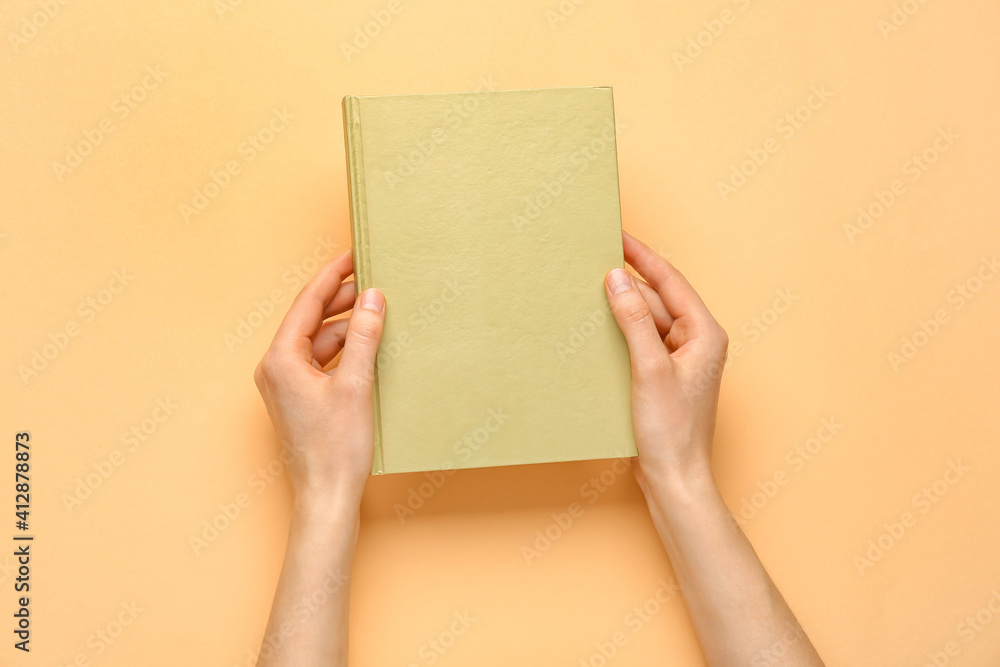 Female hands with blank book on color background