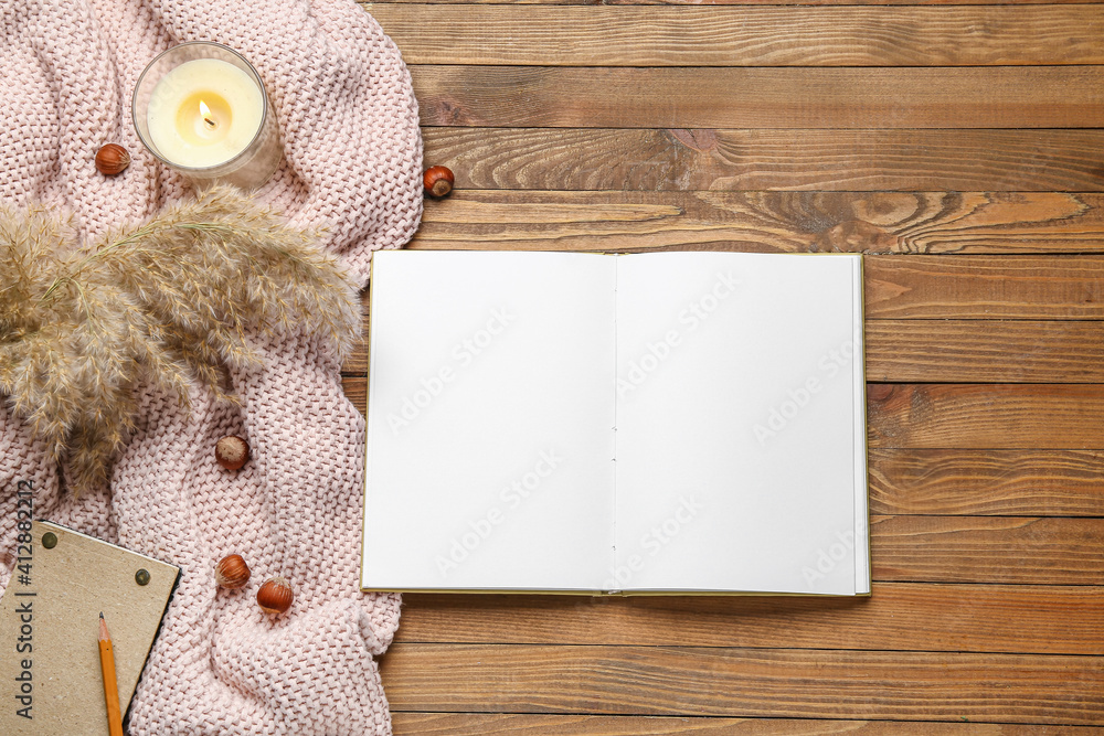 Blank open book, hazelnuts and candle on wooden background