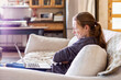 © Mint Images - Teenage girl looking at laptop on sofa