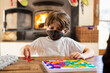 © Mint Images - young boy wearing mask playing board game at home