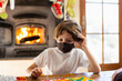 © Mint Images - young boy wearing mask playing board game at home