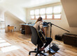 © Mint Images - Fourteen year old teenage girl playing her guitar and singing at home in loft space