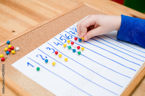 Little child doing simple math exercises. Early education, counting game. Preschool exercise for kids. Child learn to count to ten. Montessori math tool.