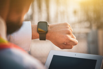 An electrician looks at the time on a black smart watch while working at workplace.