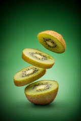 sliced kiwi fruit flying on green background