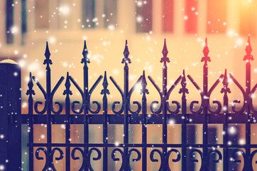 Beautiful black cast-iron fence with artistic forging. Beautiful winter background with falling snow.