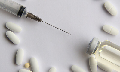 Syringes with a vaccine and different tablets on a light background