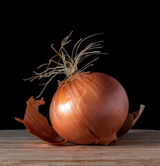 A brown onion on wood and a black background