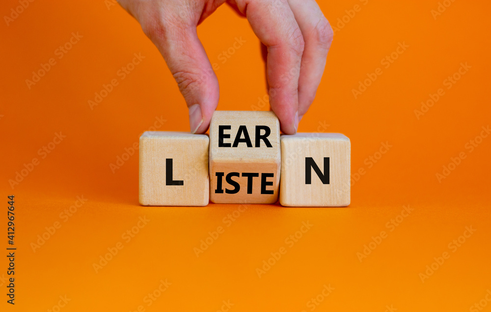 Listen and learn symbol. Businessman turns a wooden cube and changes the word 'listen' to 'learn'. Beautiful orange background, copy space. Business, education and listen and learn concept. - obrazy, fototapety, plakaty 