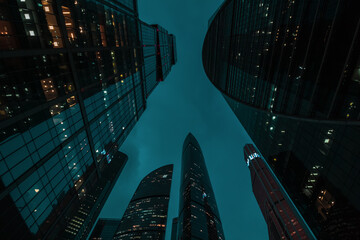 bottom up perspective view of modern city skyscraper buildings with many windows at night. Tall office buildings in Moscow city center