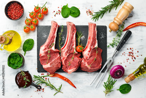 Raw veal steaks on the bone with rosemary and spices. On a white wooden background. Top view. © Yaruniv-Studio