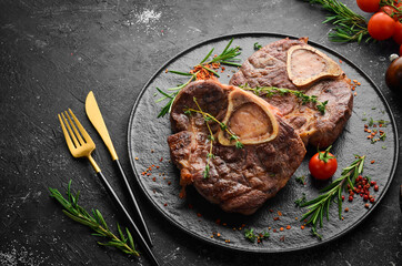 Osso buco cooked Veal shank with spices and rosemary. Barbecue meat. Top view. Flat lay top view on black stone cutting table.