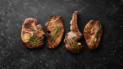 Wall Mural - Set of juicy grilled steaks and meat. Top view. Flat lay top view on black stone cutting table.