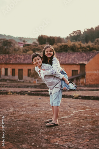 Portrait Of Brother With Sister Piggyback While Standing Outdoors
