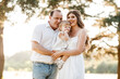 © Andriy Medvediuk - Family enjoying life together in the summer park. Happy young family outdoors. Mother, father are hugging their daughter outdoors and having fun in nature. The concept of family summer holiday.